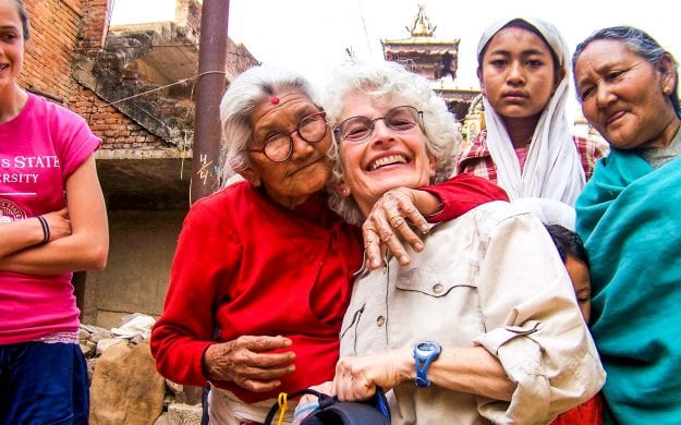 Nepal woman hugs smiling traveler