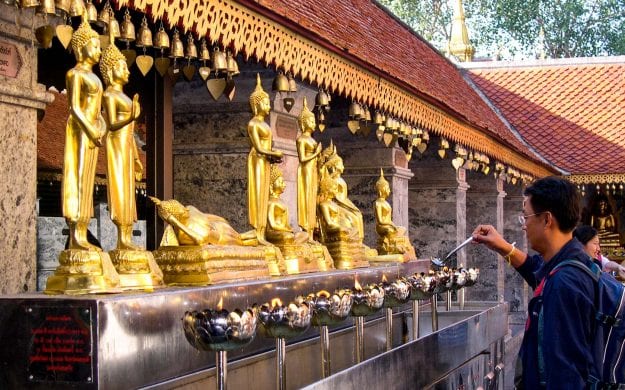 Thailand man lights candles at temple