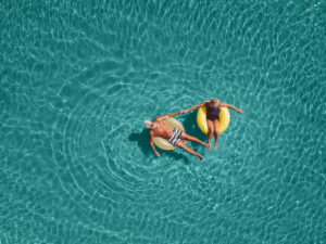High angle view photo of a couple floating in the ocean while using swimming and floating devices