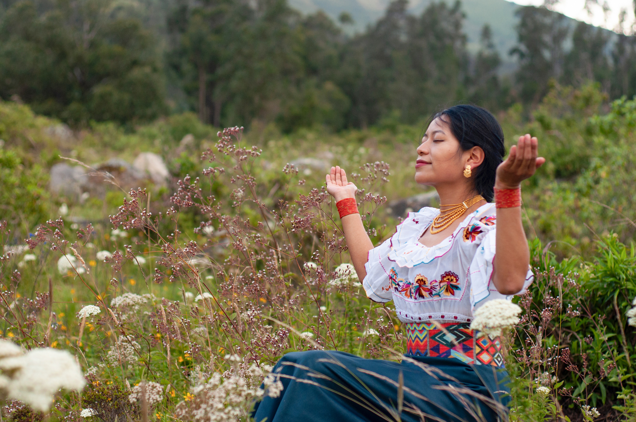 Indigenous woman sideways sitting at a thanksgiving ceremony in the andes of Ecuador with traditional Otavalo dress