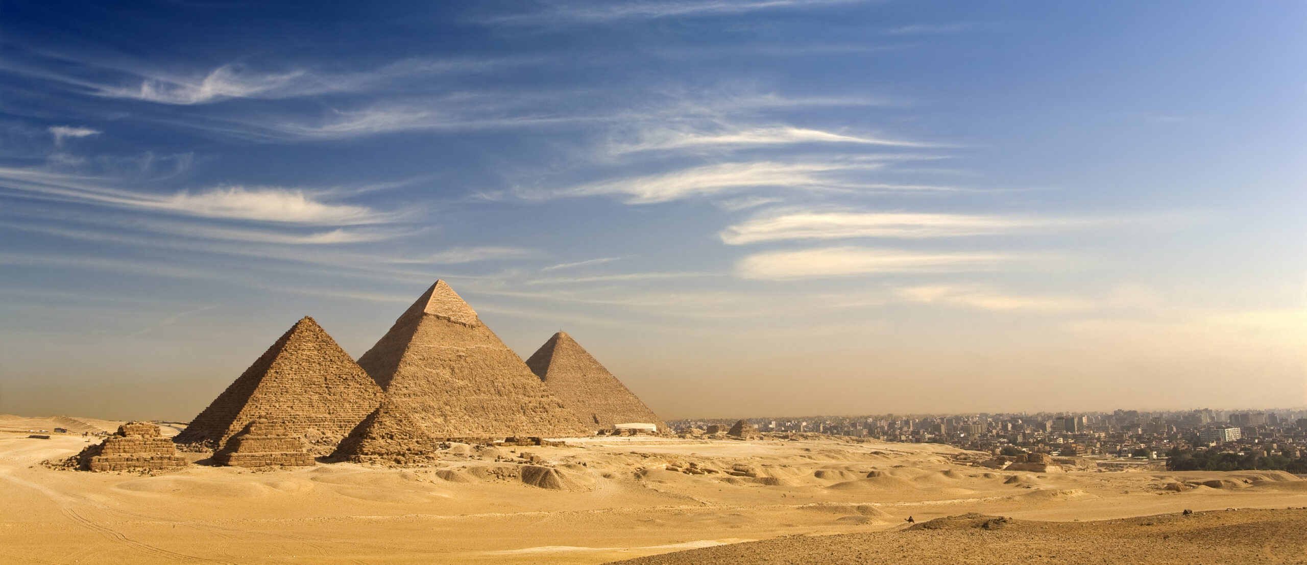 Egypt. Cairo - Giza. General view of pyramids and cityscape from the Giza Plateau (on front side: three pyramids popularly known as Queens' Pyramids; next in order from left: the Pyramid of Menkaure /Mykerinos/, Khafre /Chephren/ and Chufu /Cheops/ - known as the Great Pyramid. There is a modern city in background). The Pyramid Fields from Giza to Dahshur is on UNESCO World Heritage List