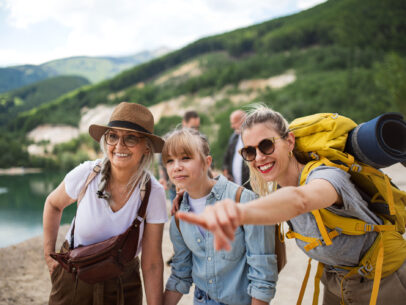 A happy multigeneration family on hiking trip on summer holiday, pointing at something.